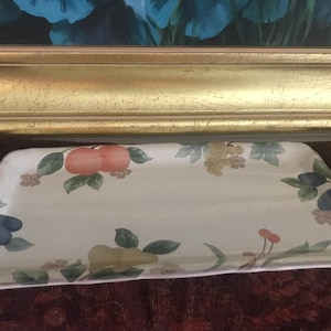 Puede incluir: Bandeja rectangular de cerámica color crema. Presenta ilustraciones de melocotones, uvas, ciruelas y otras frutas y flores. Los bordes son ligeramente curvos. Medidas en cm.