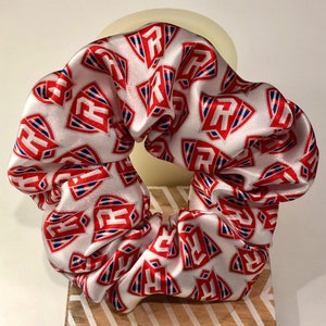 May include: White satin scrunchie with a red and blue pattern of the letter "R" inside a shield.