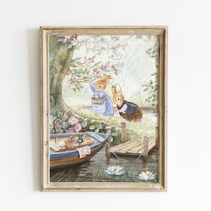 May include: A framed watercolor print depicts two rabbits near a lake. One rabbit wears a blue dress and the other a vest. A boat with a picnic basket floats on the water. The scene is framed by a wooden dock and lush greenery.