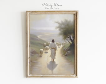 May include: A framed painting depicting Jesus walking on a path with sheep following him. The painting is set against a backdrop of a winding road, hills, and a distant sea. The sky is a soft blue with hints of pink and orange.