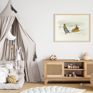 May include: A light brown wooden media console with two doors and two shelves. The console has a woven rattan front and is decorated with a wooden toy car, a wooden train, and a stack of wooden blocks. A white and beige children's play tent is in the background, along with a framed print of two rabbits pulling a sled.