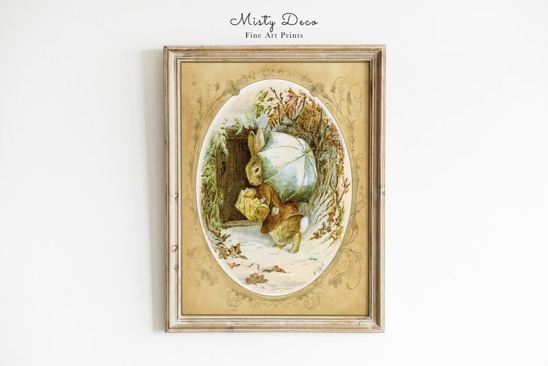 May include: A framed illustration of a rabbit holding an umbrella and a basket, walking through a snowy forest. The illustration is in a gold frame with a decorative border.