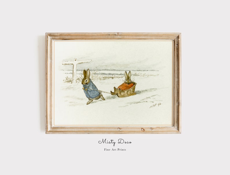 May include: A watercolor illustration of two brown rabbits in a snowy landscape. One rabbit is pulling a sled with the other rabbit sitting inside. The illustration is framed in a light wood frame.