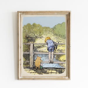 May include: A framed illustration of Winnie the Pooh and a boy standing on a wooden bridge. The boy is looking over the edge of the bridge, while Pooh is looking at him. The background is a green and blue landscape.