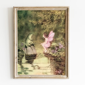 May include: A framed vintage print shows a fairy with pink wings and a frog by a pond. The fairy, in a pink dress, sits near the water, while the frog sits on a rock. The scene is set in a lush, green environment with water lilies.