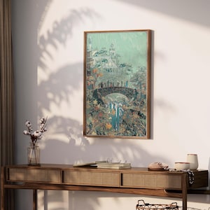 May include: A framed art print depicts a fantasy landscape with a bridge, waterfall, and castle. The artwork features a muted color palette of greens, blues, and browns, with a wooden frame. The print is displayed on a white wall above a wooden console table.