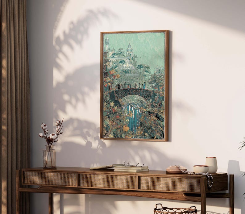 May include: A framed art print depicts a fantasy landscape with a bridge, waterfall, and castle. The artwork features a muted color palette of greens, blues, and browns, with a wooden frame. The print is displayed on a white wall above a wooden console table.