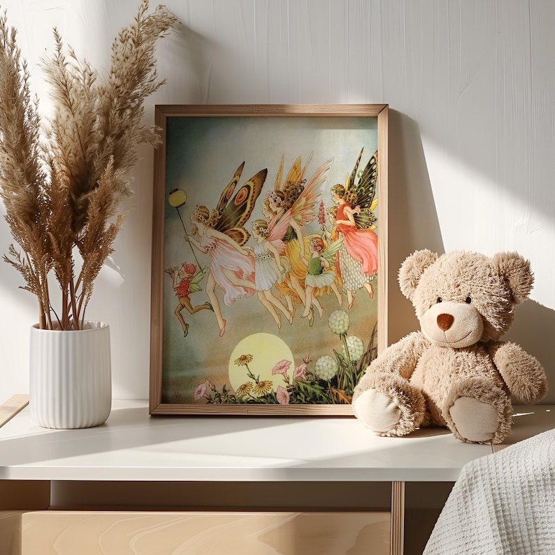 May include: A framed print featuring a vintage illustration of fairies with butterfly wings, in shades of pink, yellow, and green. A teddy bear and a vase of dried plants are on a white surface.