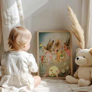 May include: A framed print featuring a vintage illustration of fairies with butterfly wings, dressed in flowing gowns, and a small figure holding a lantern. The artwork is set against a soft, dreamy background with a large moon. A teddy bear sits nearby.