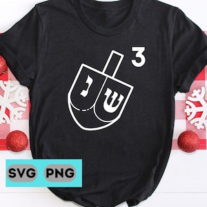 以下が含まれることがあります： 白いドレイドルのグラフィックが描かれた黒いTシャツ。ドレイドルには、ヌン、ギメル、ヘイ、シンというヘブライ文字が書かれています。ドレイドルの上に数字の3があります。