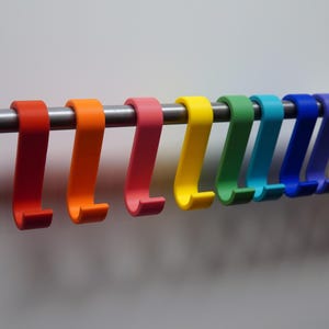 May include: A collection of colorful, S-shaped hooks in a rainbow of hues, including red, orange, pink, yellow, green, teal, blue, white, gray, and black. The hooks are mounted on a silver metal rod, perfect for organizing items.