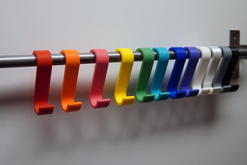 May include: A collection of colorful, S-shaped hooks in a rainbow of hues, including red, orange, pink, yellow, green, teal, blue, white, gray, and black. The hooks are mounted on a silver metal rod, perfect for organizing items.