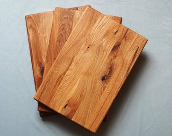 Oak cutting board, finished with linseed oil varnish, available in various sizes, with recessed handles and optional rubber feet.