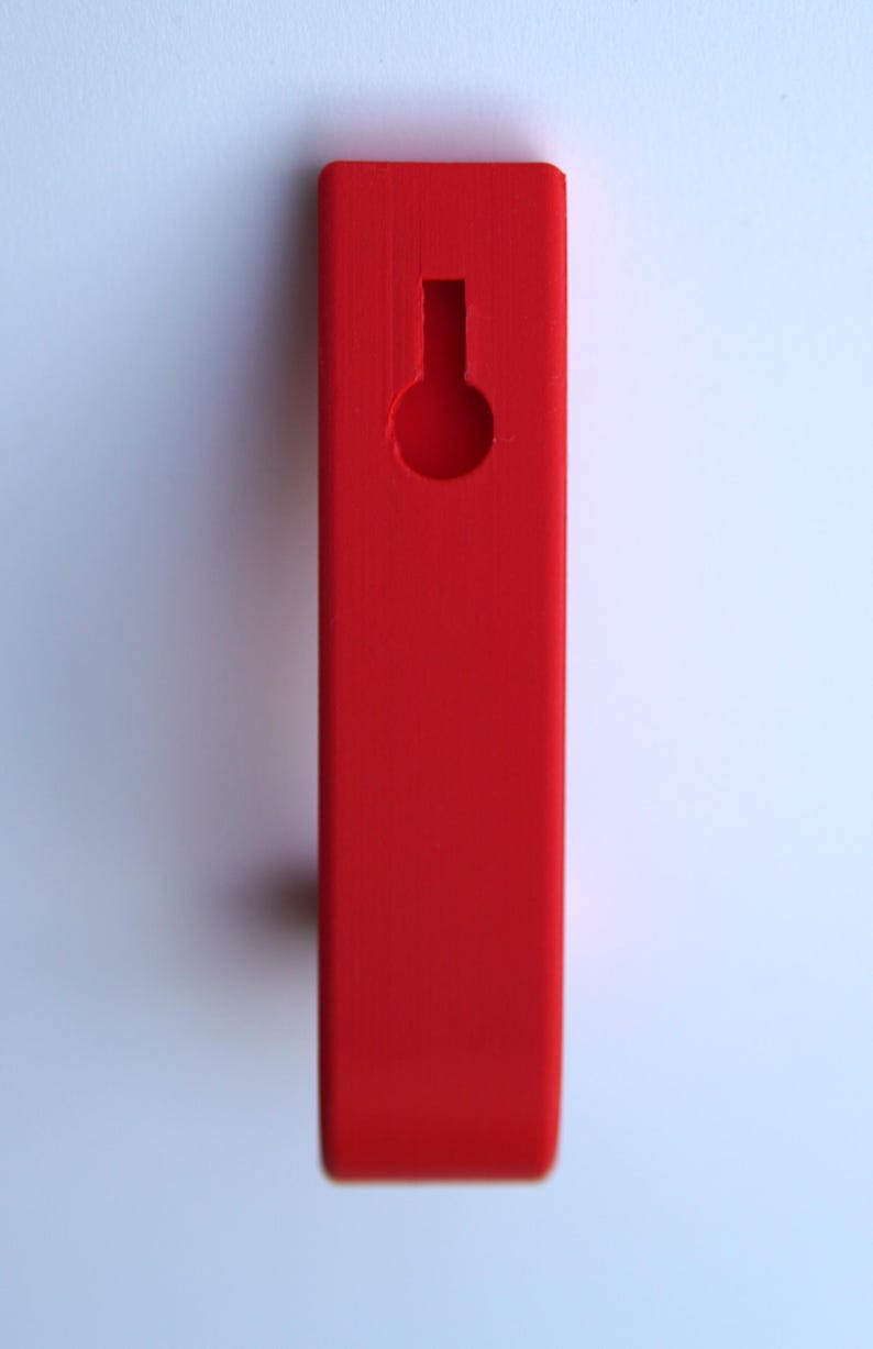 May include: A bright red wooden hook with a round hole in the center. The hook is designed for hanging items on a wall.