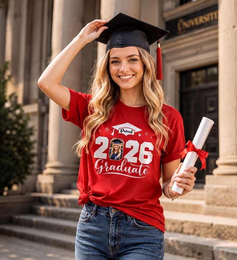 A smiling young woman wearing a graduation cap and gown, holding a diploma, standing in front of a university building.