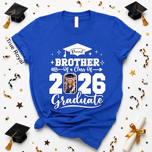 A blue t-shirt with a graduation cap and tassel, surrounded by gold and black confetti, and a graduation cap.