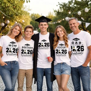 A group of five people, including a young man in a graduation cap, posing for a photo. They are all wearing white t-shirts with graduation-related text and graphics.