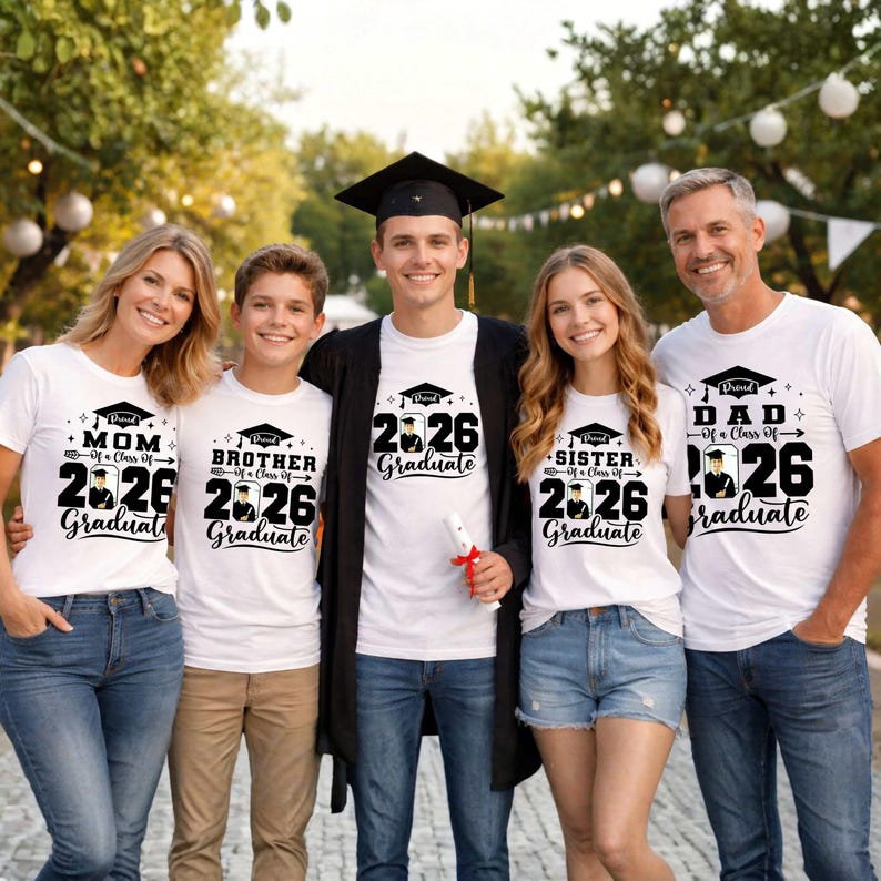 A group of five people, including a young man in a graduation cap, posing for a photo. They are all wearing white t-shirts with graduation-related text and graphics.