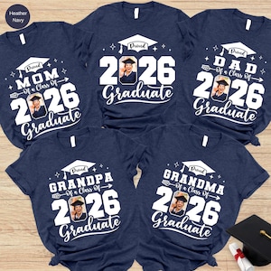 a collection of five navy blue t-shirts with white text and graphics, likely representing a graduation celebration.