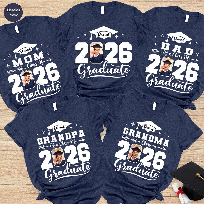 a collection of five navy blue t-shirts with white text and graphics, likely representing a graduation celebration.