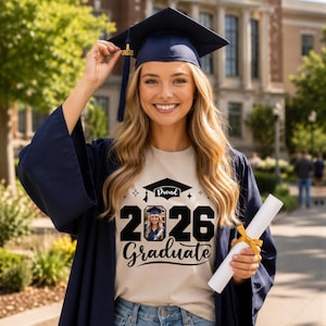 A smiling young woman in a graduation gown and cap holding a diploma stands in front of a brick building.