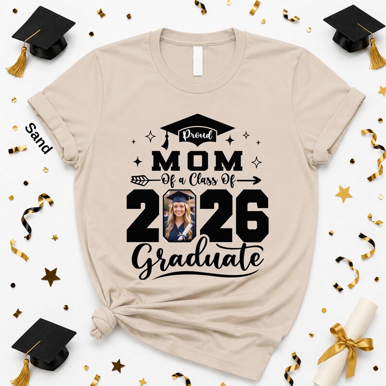A beige t-shirt with a graduation-themed design, surrounded by graduation caps, confetti, and a photo of a smiling woman.