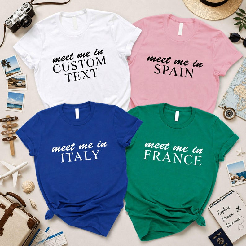 four t-shirts with custom text printed on them, arranged on a surface with various travel-related items such as a camera, a hat, and a map.
