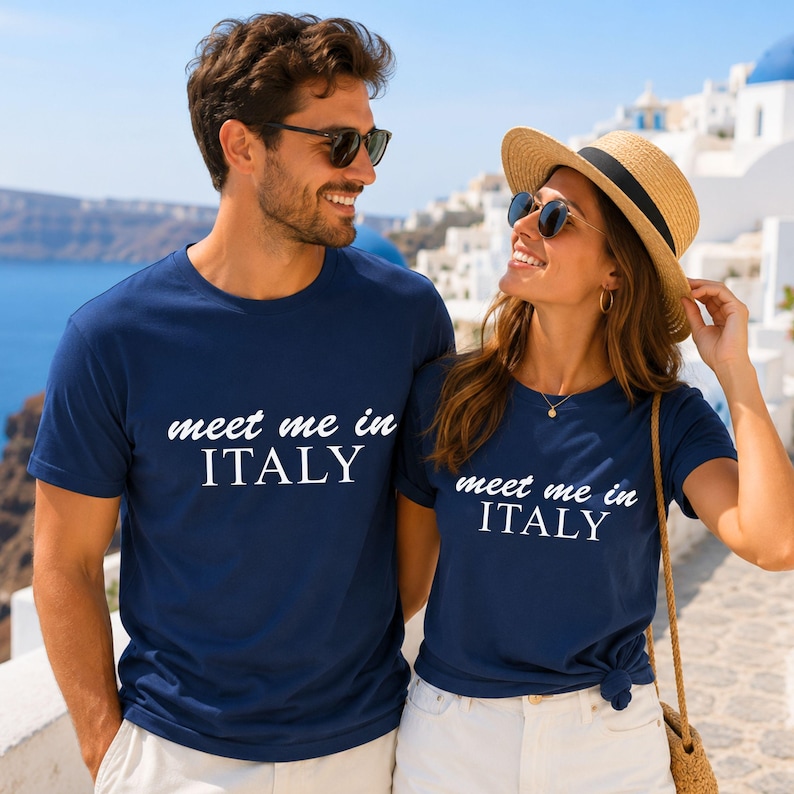 A man and a woman wearing matching blue t-shirts with the text "Meet me in ITALY" are standing together and smiling.