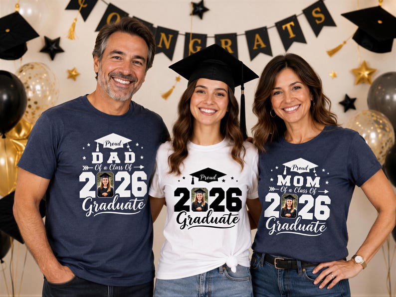 Three people, two women and one man, are standing together and smiling in front of a graduation backdrop. They are all wearing t-shirts with the same design, which features a graduation cap and the text "Graduate" along with the year "2026".