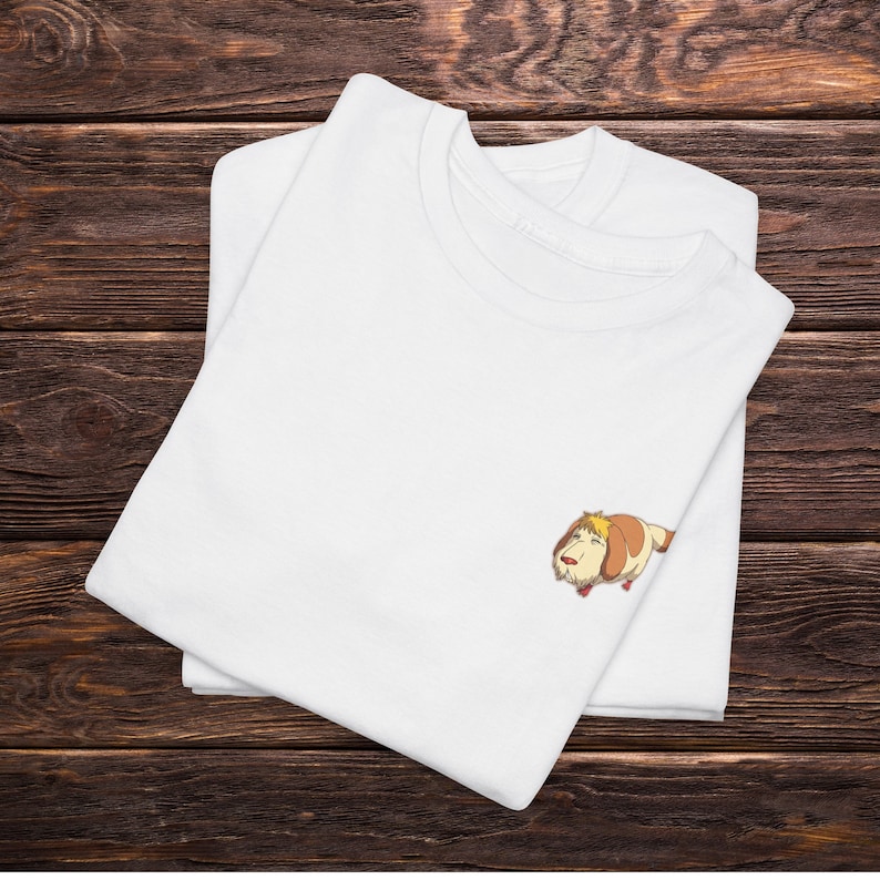 May include: White t-shirt with a cartoon dog illustration. The dog is brown and white with a yellow head and is lying down.