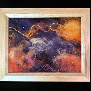 May include: A framed artwork depicting a galaxy with swirling strands of orange, red, and white yarn on a dark purple background. The yarn is interspersed with small, iridescent beads.
