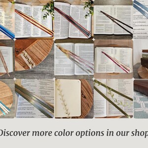 May include: Assortment of open books with colorful ribbon bookmarks. The bookmarks are in various colors, including blue, green, and red. Some books have decorative leaf accents. The text "Discover more color options in our shop!" is at the bottom.