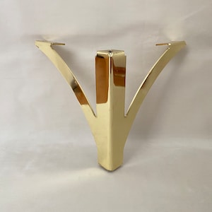 May include: Gold metal furniture leg with a triangular base and three curved arms.