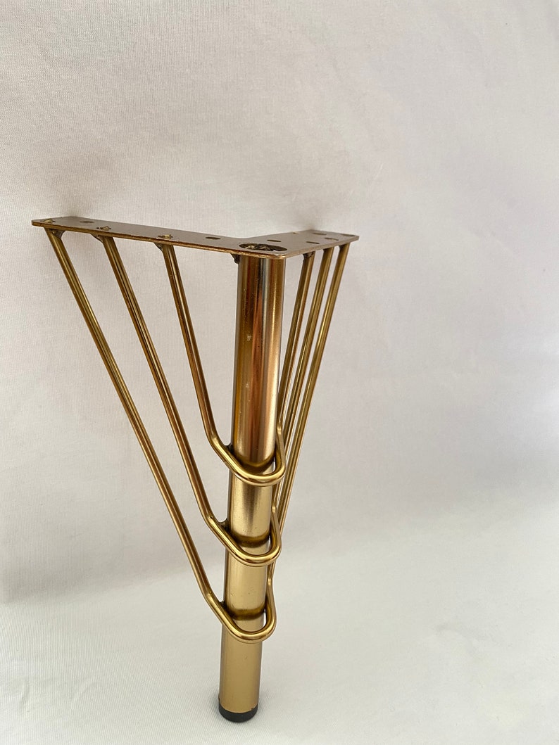 May include: Gold metal furniture leg with a square base and five curved supports. The leg is approximately 12 inches tall.