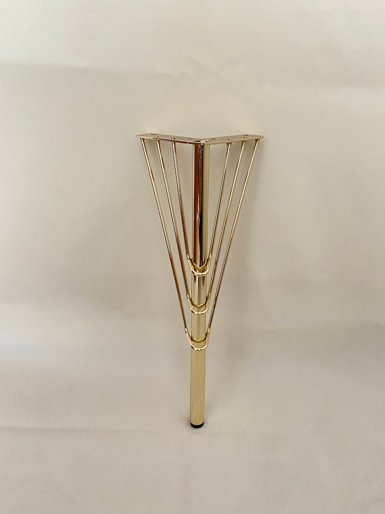 May include: Gold metal table leg with a triangular base and a decorative cage design.