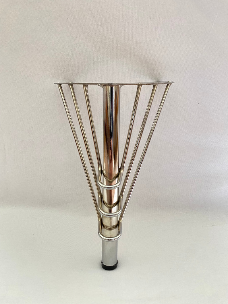 May include: A silver metal table leg with a circular base and a cage-like design around the top.