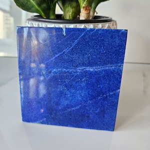 Può includere: Un sottobicchiere quadrato in lapislazzuli blu lucido. Il sottobicchiere è su una superficie bianca.