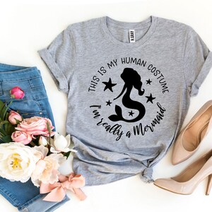 May include: Gray t-shirt with a black graphic that says "This is my human costume I'm really a mermaid" with a mermaid silhouette and stars.
