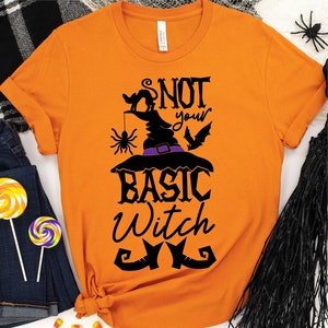 May include: Orange t-shirt with a black graphic of a witch's hat, a black cat, a spider, and the text "Not your basic witch".
