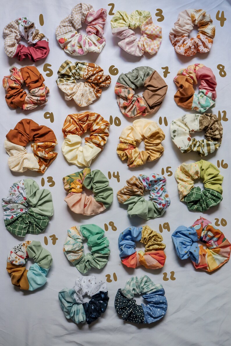 May include: Twenty-two colorful scrunchies made from different patterned fabrics. The scrunchies are arranged in rows on a white surface.