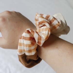 May include: A brown and white checkered scrunchie with a brown fabric backing.