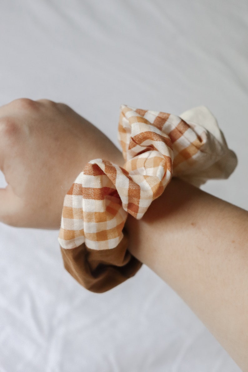 May include: A brown and white checkered scrunchie with a brown fabric backing.
