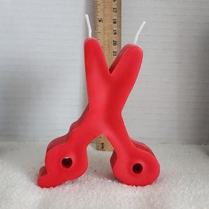 May include: Red plastic birthday candle shaped like a pair of scissors.