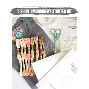 Könnte beinhalten: Ein graues T-Shirt mit einem gestickten Blumenmuster auf der Vorderseite. Das Set enthält Stickgarn in verschiedenen Beige-, Rosa- und Brauntönen, eine Stickerschere, einen Stickrahmen und eine Anleitung für Stickgrundlagen.