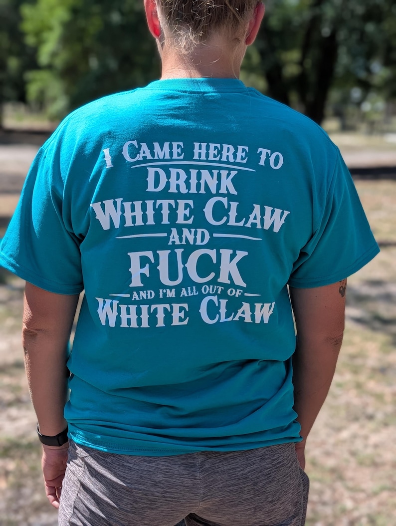 May include: Teal t-shirt with white text that reads "I CAME HERE TO DRINK WHITE CLAW AND FUCK AND I'M ALL OUT OF WHITE CLAW." The shirt is short-sleeved.
