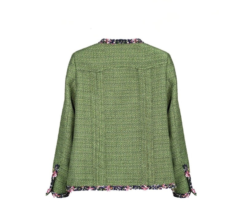 Op de afbeelding: Een groen tweed jasje met een zwarte en roze bies. Het jasje heeft een kraag en lange mouwen.