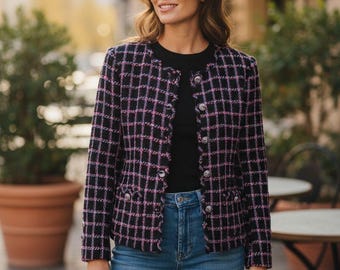 Könnte beinhalten: Eine schwarz-rosa karierte Jacke mit silbernen Knöpfen. Die Jacke wird über einem schwarzen Oberteil und mit einer blauen Jeans kombiniert. Die Jacke hat ein klassisches, maßgeschneidertes Design, das für verschiedene Anlässe geeignet ist.