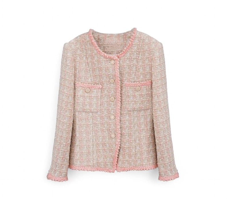 K&ouml;nnte beinhalten: Hellrosa und beige Tweedjacke mit rundem Ausschnitt und langen &Auml;rmeln. Die Jacke hat eine rosa Einfassung an den Kanten, Taschen und Knopfverschl&uuml;ssen. Der Stoff hat eine gewebte Textur.