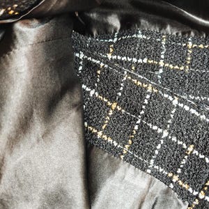 May include: Close-up of the inside of a black and white tweed handbag with a black satin lining.