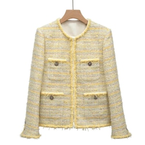 Pode incluir: Uma jaqueta de tweed listrada em amarelo e branco com fecho de correr e bolsos de aba. A jaqueta tem uma bainha desfiada.